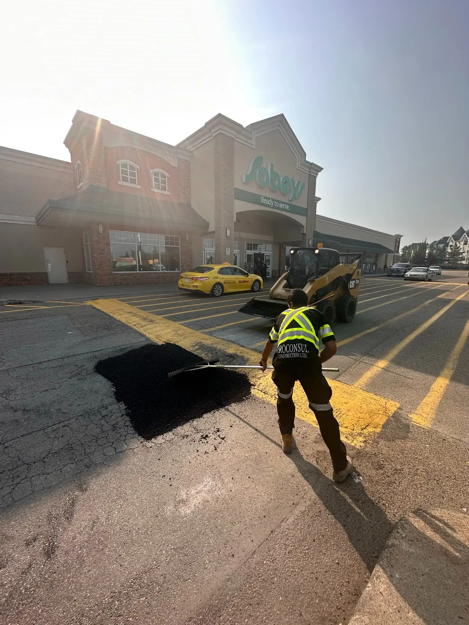 Worker patching asphalt in grocery store parking lot